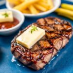 Golden garlic butter steak bites piled on a rustic plate with parsley garnish